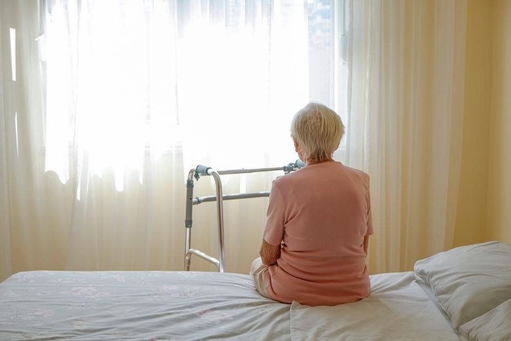 An elderly woman sitting alone in a nursing home. A lawyer can explain how to anonymously report a nursing home.