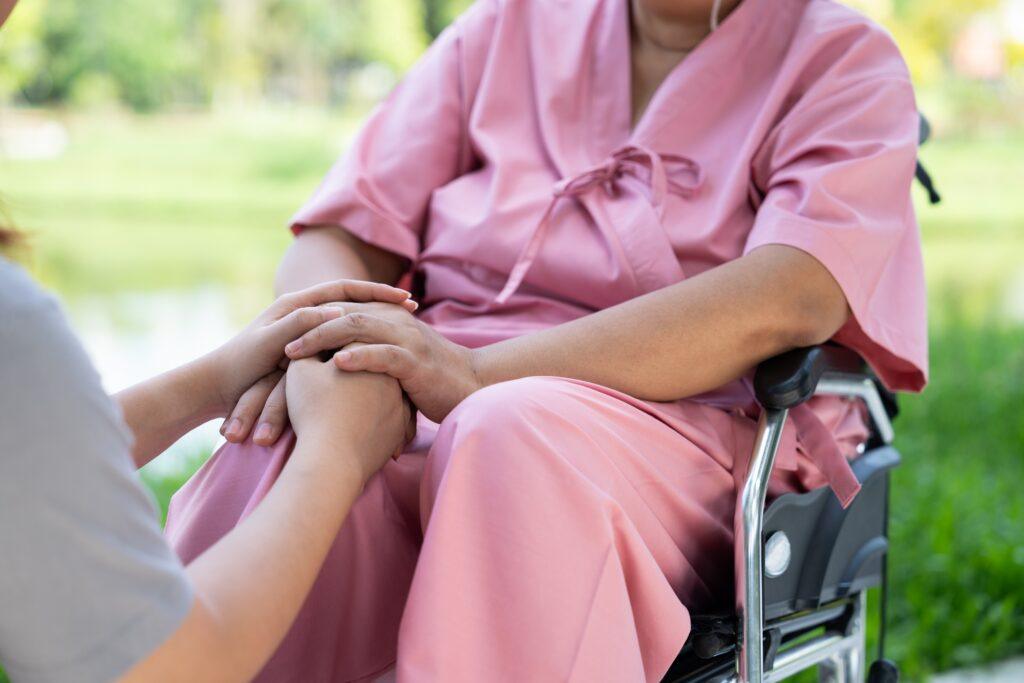 an older woman sitting by a window facing outside for an article that explains the average nursing home neglect settlement.